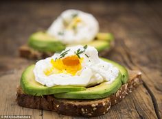 avocado toast with an egg in the middle on a wooden surface, ready to be eaten