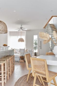 a living room filled with furniture next to a stair case in a home kitchen and dining area