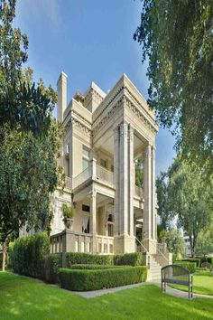 a large white house sitting in the middle of a lush green park with lots of trees