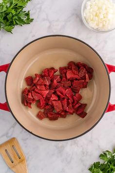 chopped beets in a pot with onions and parsley next to it on a marble countertop