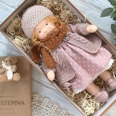 a small doll in a box next to a teddy bear