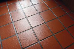 a bathroom floor with red tiles on the bottom and one tile in the middle that has been grouted