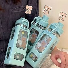 the woman is holding four water bottles in her hands, both with teddy bears on them