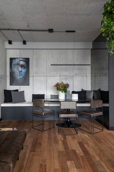 a living room filled with furniture next to a wall mounted art piece and a potted plant