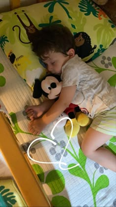 a small child laying on top of a bed with a stuffed animal next to it