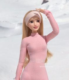 a barbie doll is standing in the snow wearing a pink dress and headband with her hand on her hair