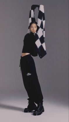 a woman in black and white poses with a checkerboard scarf on her head