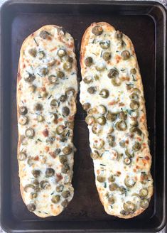 two pieces of pizza with olives and cheese on a baking sheet in an oven