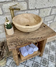 a bathroom sink sitting on top of a wooden table next to a potted plant