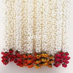 flowers are arranged on the side of a white wall with red, yellow and orange petals