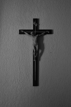 a black and white photo of a crucifix hanging on the side of a wall