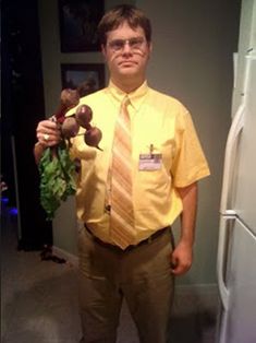 a man in a yellow shirt and tie is holding some fruit while standing next to a refrigerator