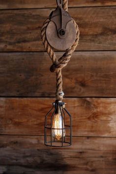 an old fashioned light hanging from a rope on a wooden wall with wood planks