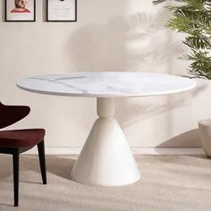 a white marble dining table with two chairs in front of it and pictures on the wall