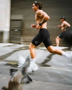 a man running in the street with a bird flying next to him on his feet