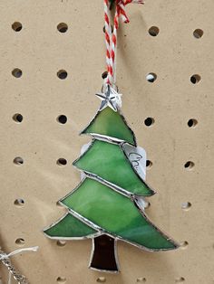 a stained glass christmas tree ornament hanging on a wall with a candy cane