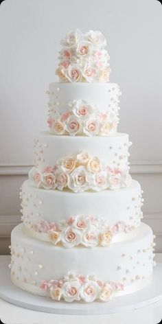 a wedding cake with white and pink flowers on the bottom tier, sitting on top of a table