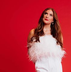 a woman with long hair wearing a white dress and feather boa around her shoulders