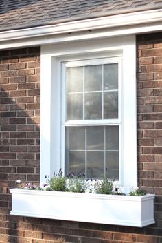 a brick house with a white window and flower box