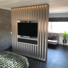 a bed room with a neatly made bed and a flat screen tv on the wall