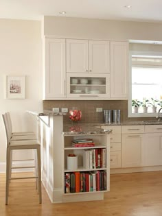 a kitchen with white cabinets and an island in front of the stove top oven is filled with books