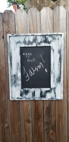 a chalkboard sign on a wooden fence