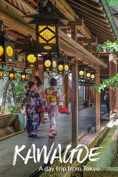 two women in kimonos are walking down the walkway with lanterns hanging above them