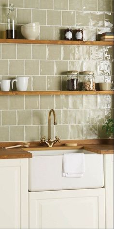 a kitchen with white cabinets and open shelving above the sink is filled with dishes