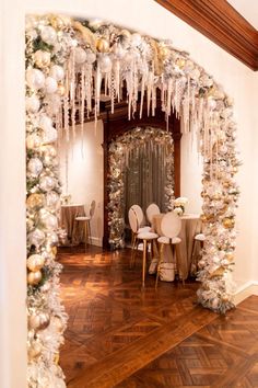 an archway decorated with white and gold christmas decorations, snowflakes and icicles