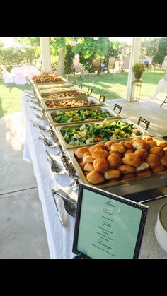 there are many different types of food on the table at this outdoor event, including croissants and salads