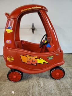 a red toy car with lightning bolt stickers on it's side and steering wheel