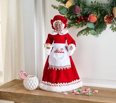 a red and white christmas doll sitting on top of a wooden table next to candy canes