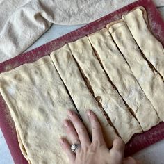 a person is rolling out dough on a red mat