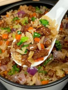 a spoon full of rice with meat and vegetables