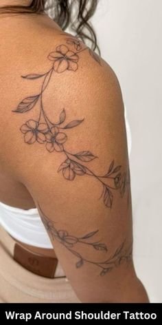 the back of a woman's shoulder with flowers on it and text that reads wrap around shoulder tattoo