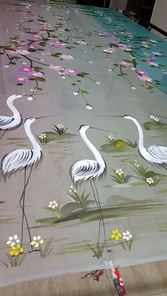 two white birds standing on top of a table covered in water lilies and daisies