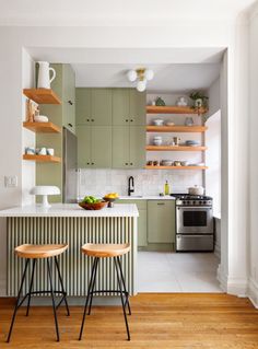 two stools sit in front of an island with open shelving on the wall