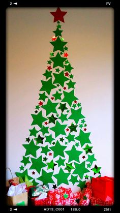 a christmas tree made out of paper with red and green stars on the top, surrounded by presents