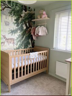 a baby's room with a crib and deer wallpaper on the walls