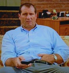 a man sitting on a couch holding a remote control