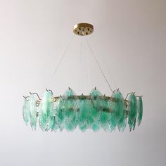 a green chandelier hanging from a ceiling in a room with white walls and flooring