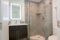 a bathroom with a walk in shower sitting next to a toilet and sink under a mirror