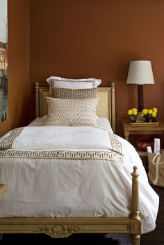 a white bed sitting in a bedroom next to a painting on the wall above it