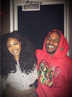 a man and woman standing next to each other in front of a door wearing red hoodies