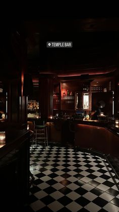 a dimly lit bar with checkered flooring and black and white tiles on the floor