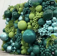 a large green and blue sculpture made out of grapes, berries, and other things