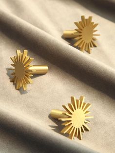 two gold sunbursts sitting on top of a white sheet covered in fabric