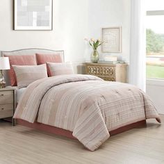 a bed in a bedroom with a pink comforter and matching pillows on the bed