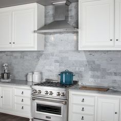 a stove top oven sitting inside of a kitchen next to white cabinets and counter tops