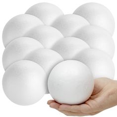 a hand is holding a white ball in front of several balls on a white background